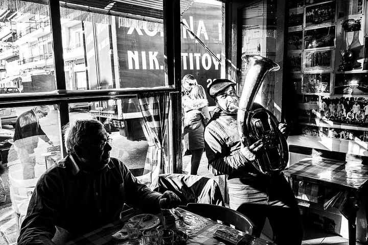 Black and white photograph of brass musicians performing inside a café in Florina.
