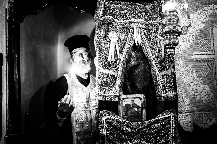 Black and white photograph of Papa Yannis performing a christening inside the church of Agios Minas, Karpathos.