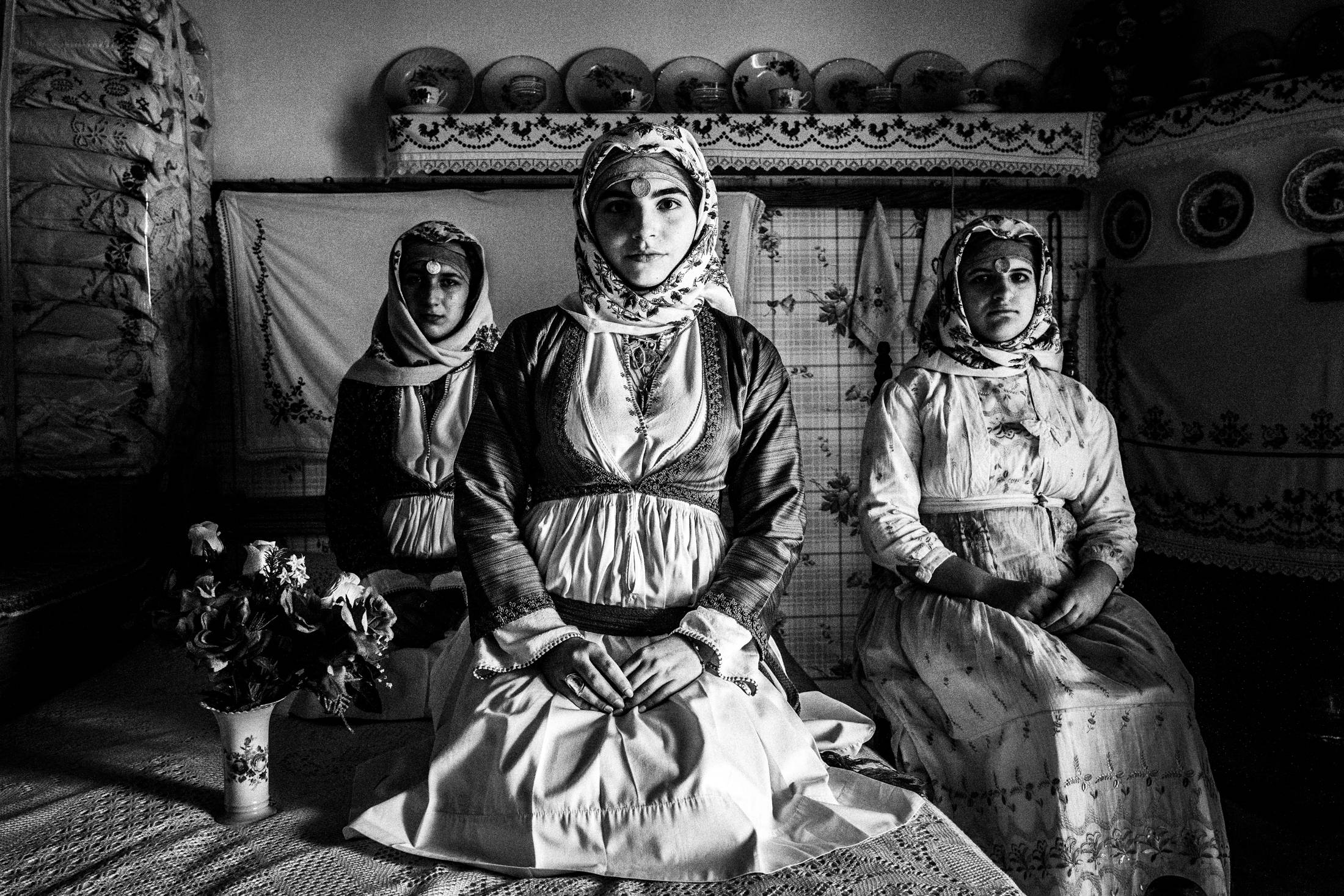 Three young women wearing the local dresses of Apollona, Rhodes, inside a local house
