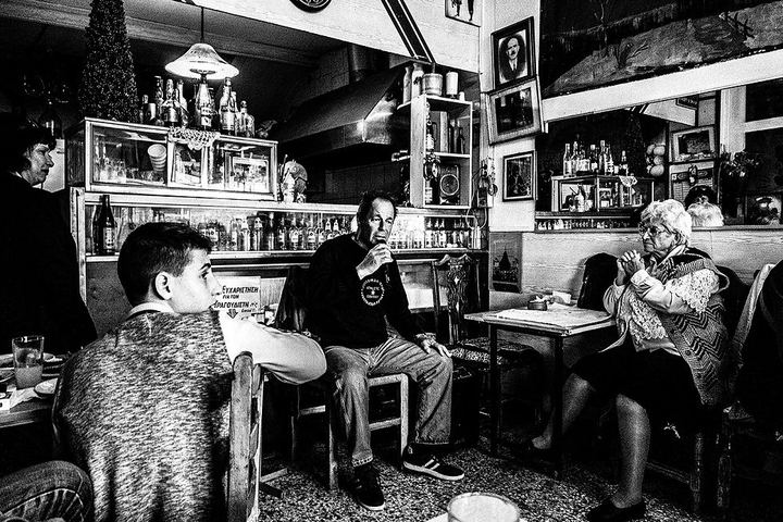 Black and white photograph of Theo singing into a microphone inside Theoklitos Café.