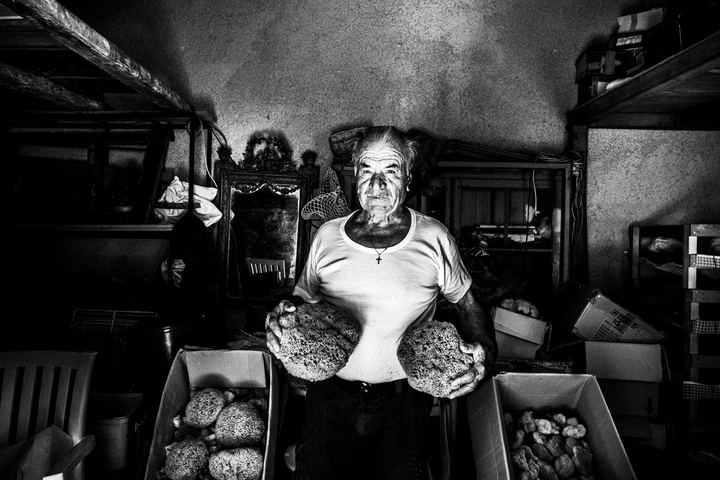 Black-and-white photograph of Antonis Kampourakis inside his sponge warehouse on Kalymnos.