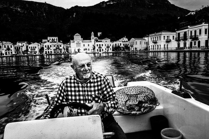 Black and white photograph of Stavros Choulis piloting his boat around Kastellorizo.
