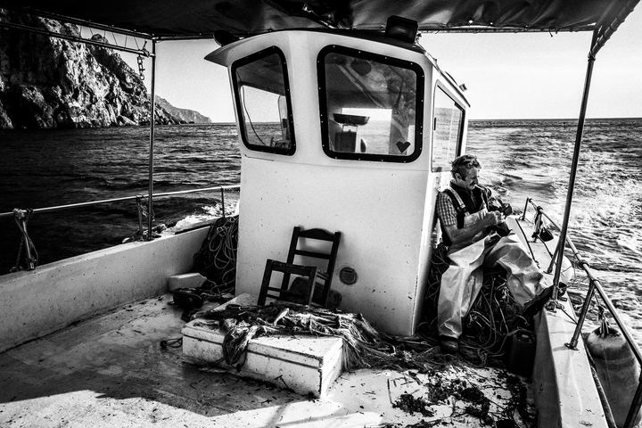 Black and white photograph of Yorgos removing fish from a net near Diafani, Karpathos.