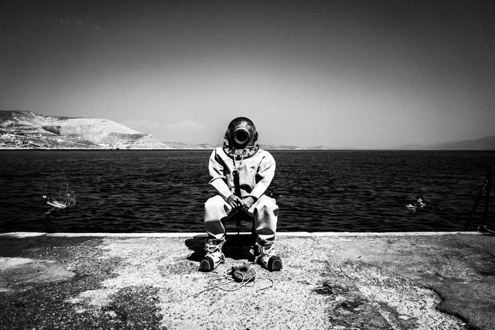 Black-and-white photograph of Dimitris wearing a traditional diving suit on Kalymnos.