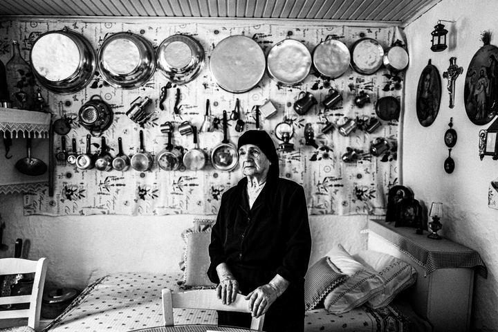 Zafeirenia standing behind a stair in her kitchen, inside a traditional house in Anogia, Crete