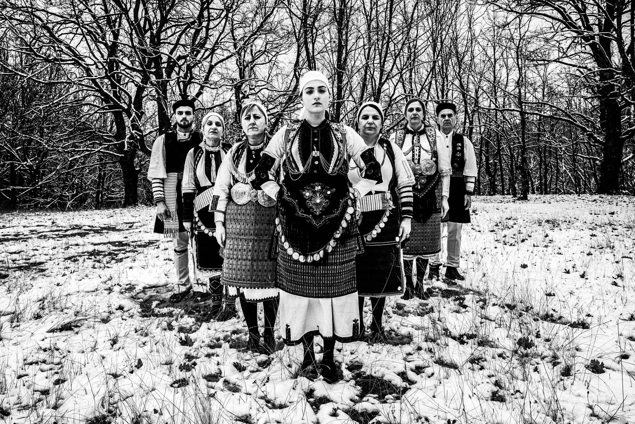 A group of people wearing the local costumes of Kladorachi in Florina, standing in an arrow formation in the snow