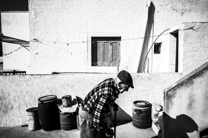 An elderly man walking past a white-washed house in Santorini