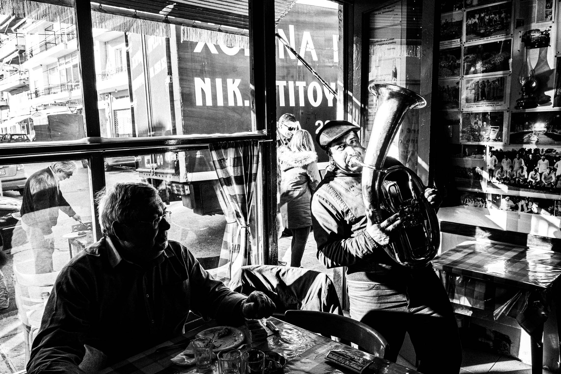 Black and white photograph of musicians playing brass instruments inside a café in Florina during the Christmas season.