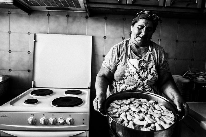 Ayshe holding a large tray of zucchini blossoms in her kitchen in Platani, Kos