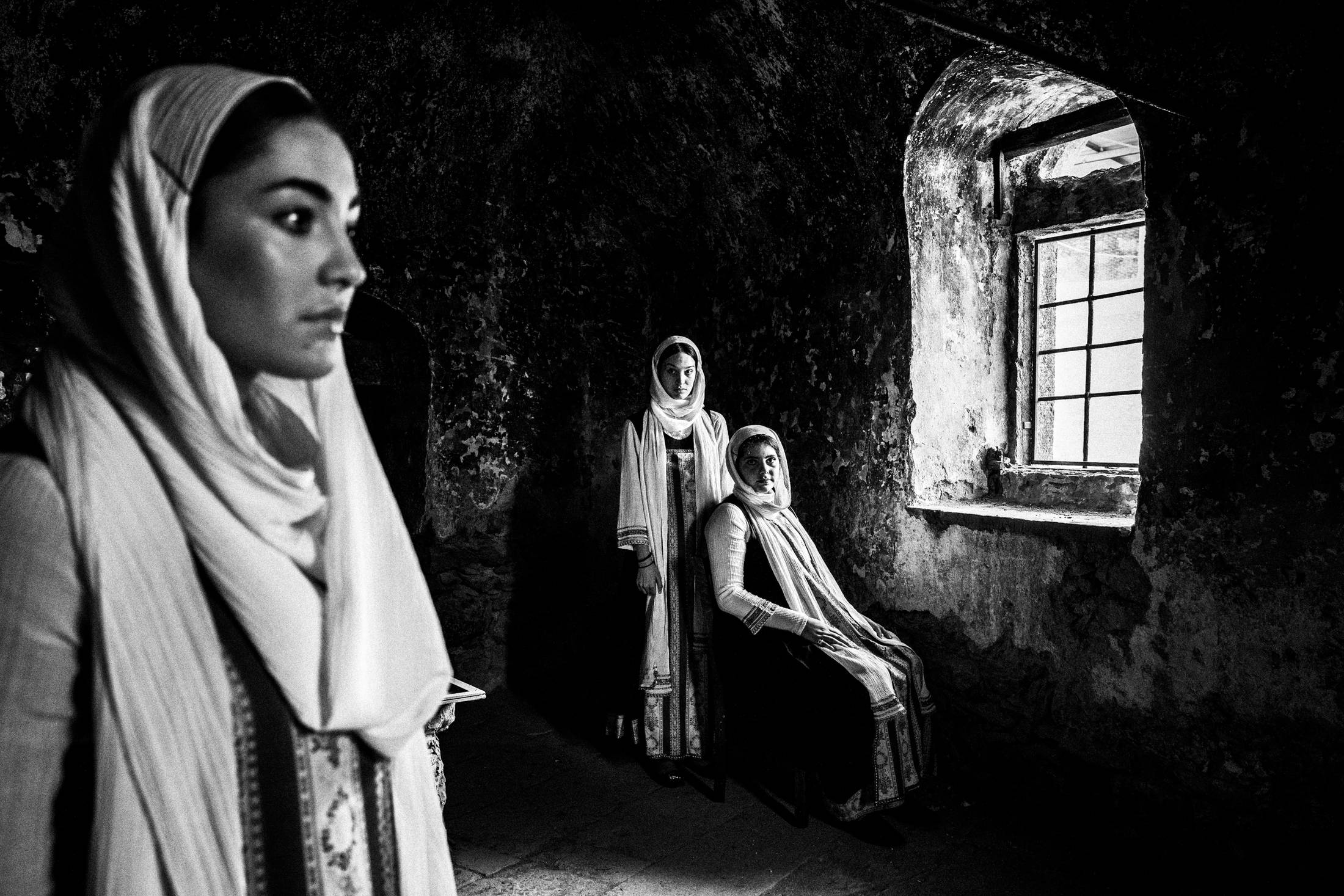 Women in the local dresses of Elata standing inside an old abandoned stone house