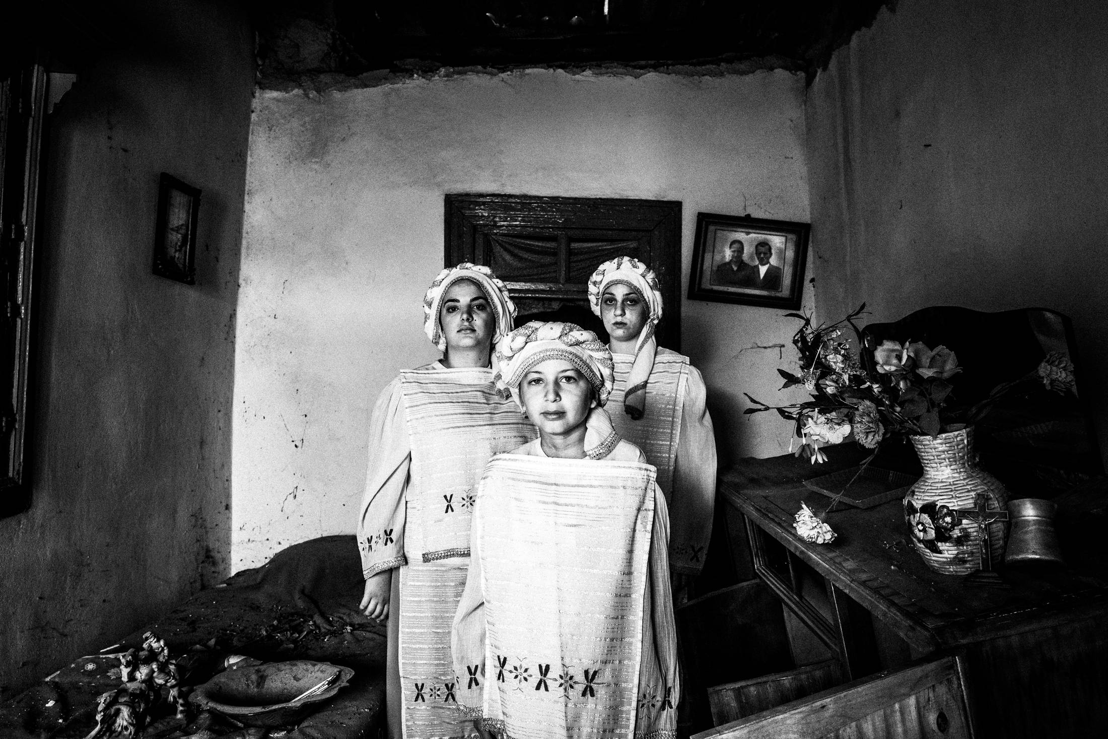 Three young women wearing the local costumes of Dafnonas standing inside an old abandoned local house.