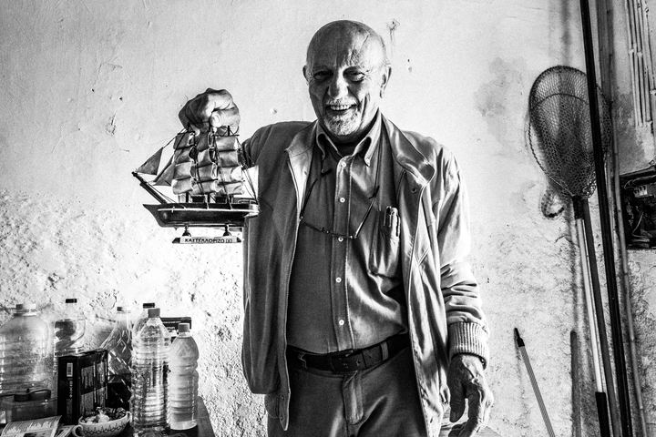 Black and white photograph of Stavros Choulis with a model ship inside his home in Kastellorizo.
