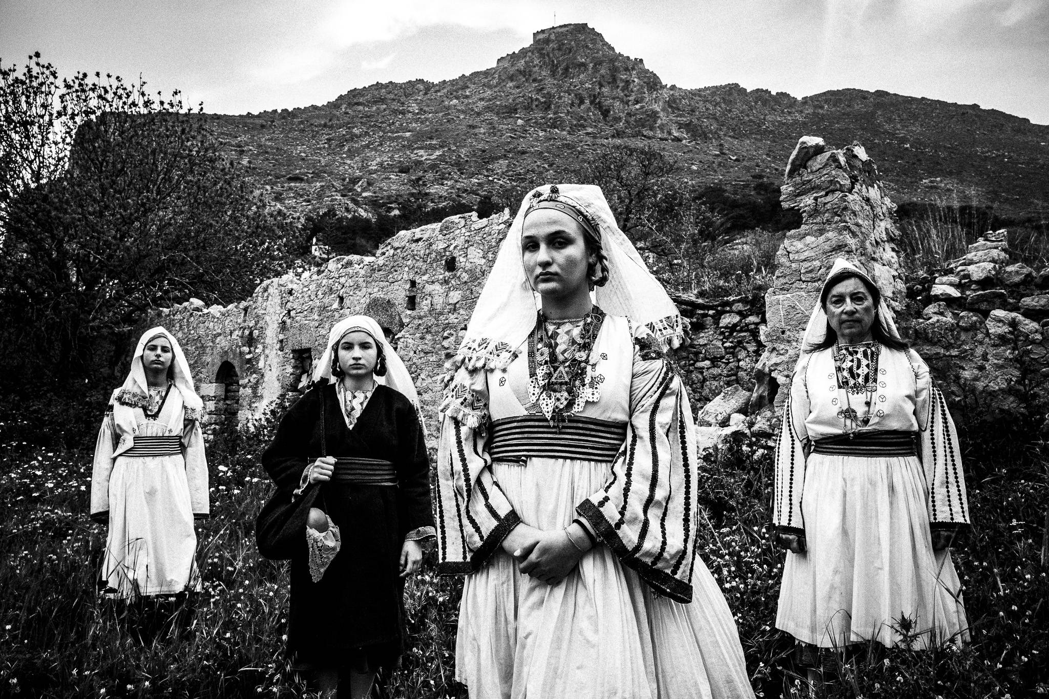 Four women wearing the local costumes of Tilos, stand by the fortyfying walls of Megalo chorio on the island.