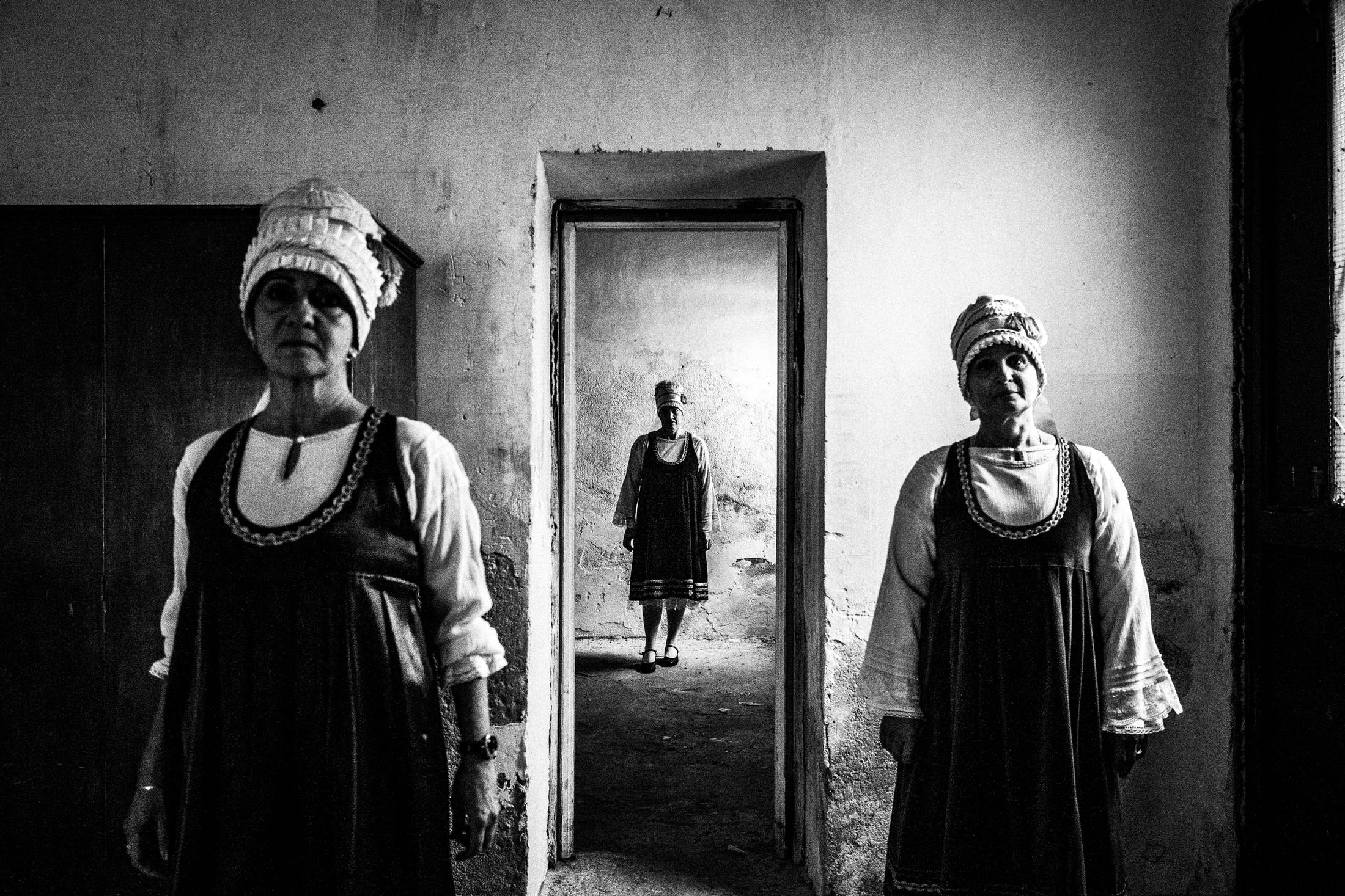 Women wearing the local costumes of Neochori standing inside a local abandoned house