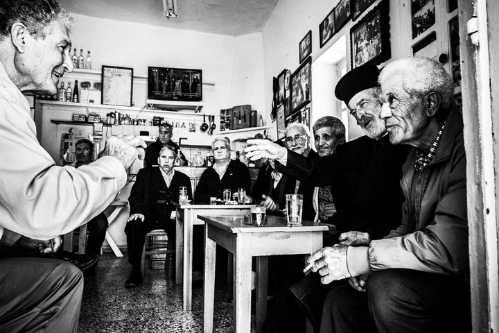 Black and white photograph of men talking at the central café in Olympos, Karpathos.