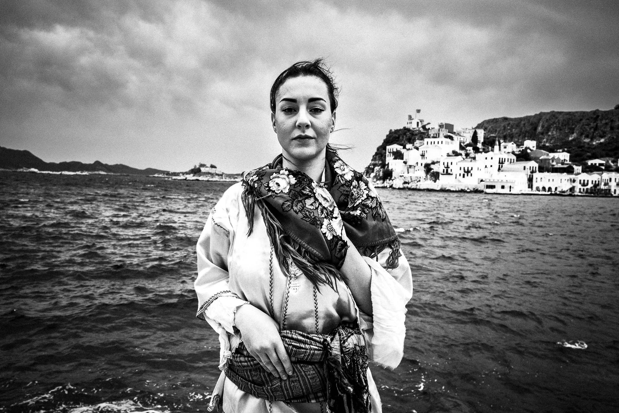 A woman wearing the local dress of Kastellorizo, standing before the sea on the island