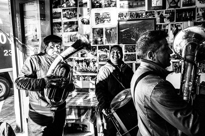 Black and white photograph of a brass band performing inside a café in Florina during winter.