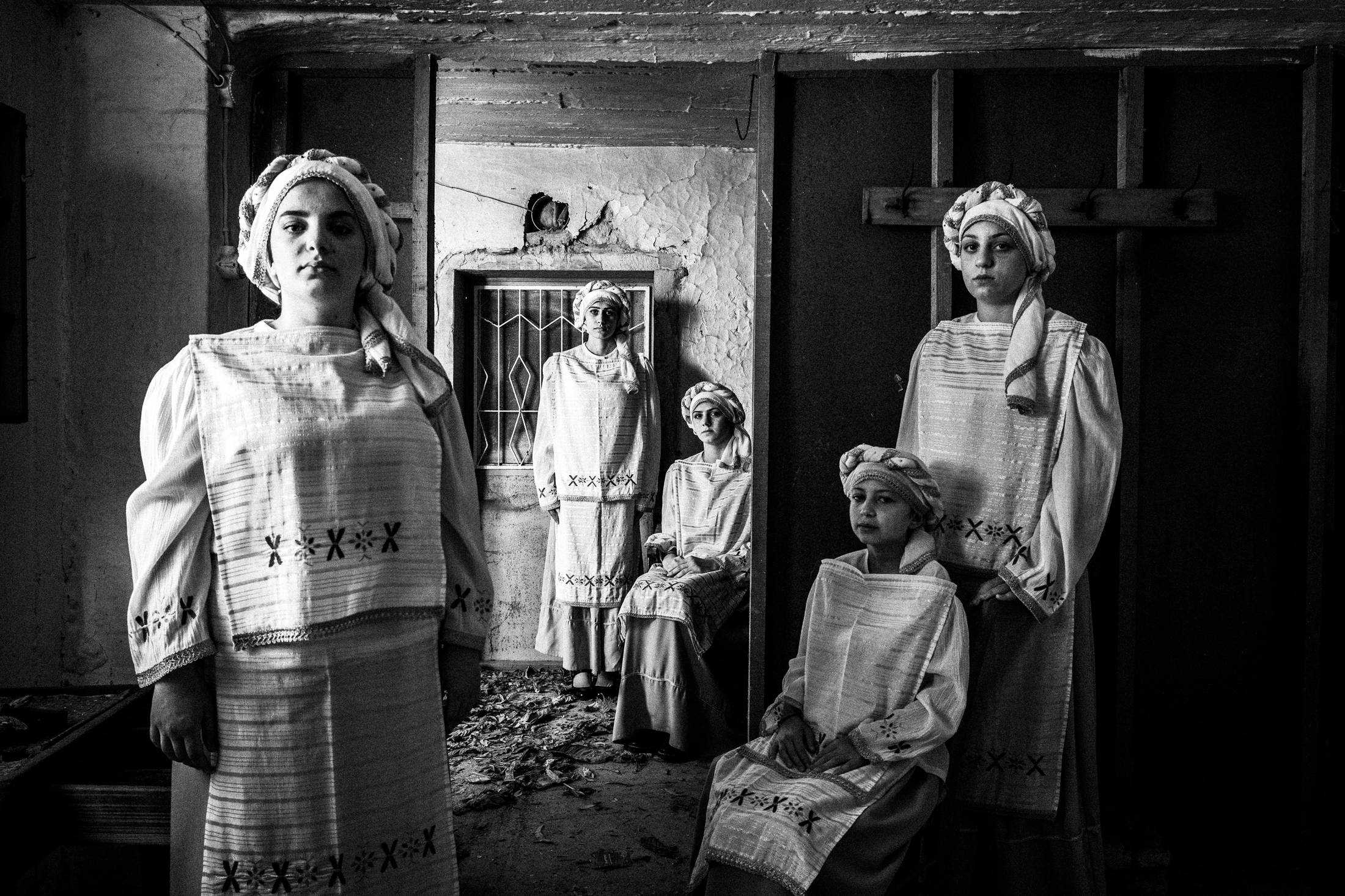 Five young women Wearing the local costumes of Dafnonas standing inside an old abandoned local house.