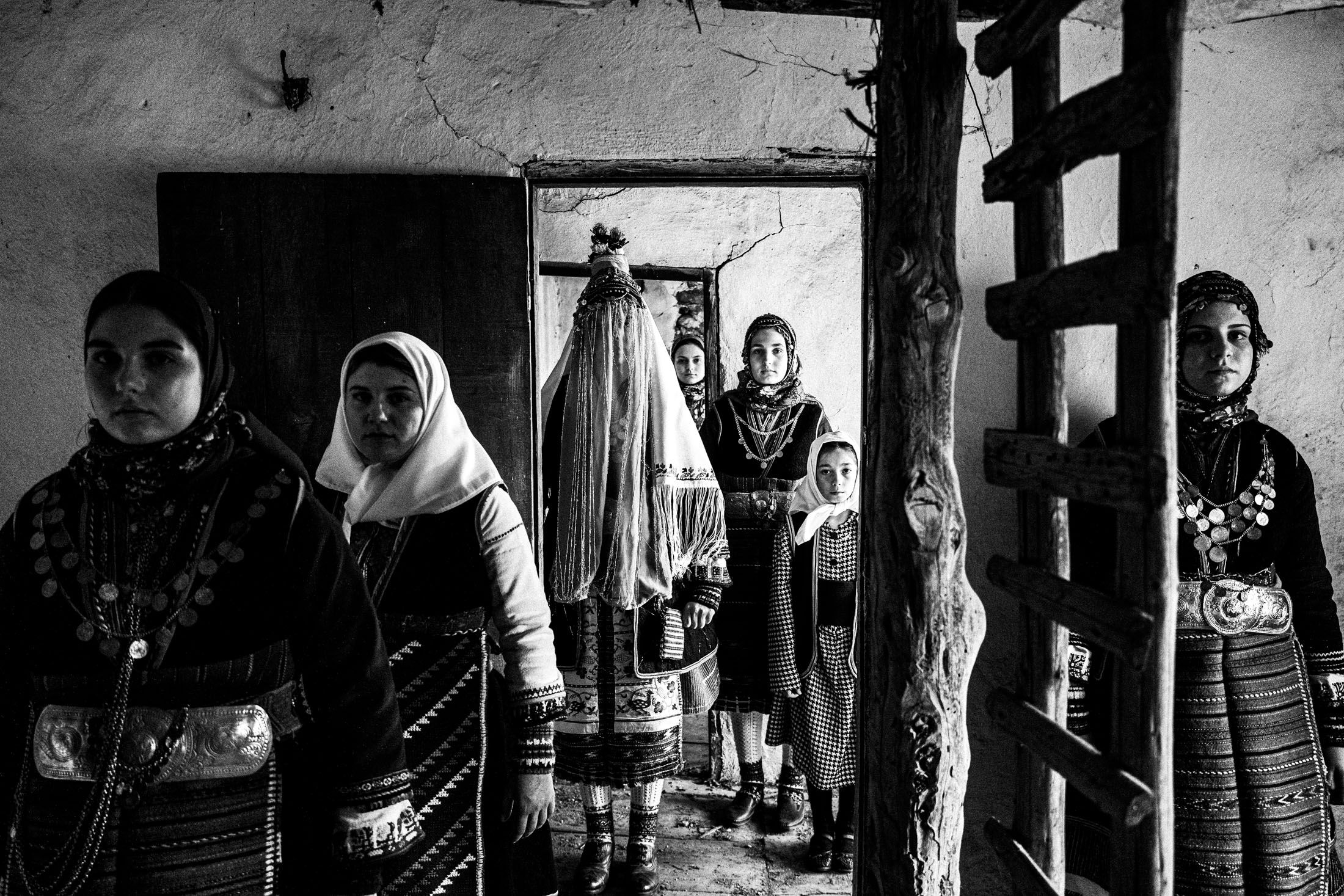 A group of people wearing the local costumes of Orini Serron, inside an old local abandoned house