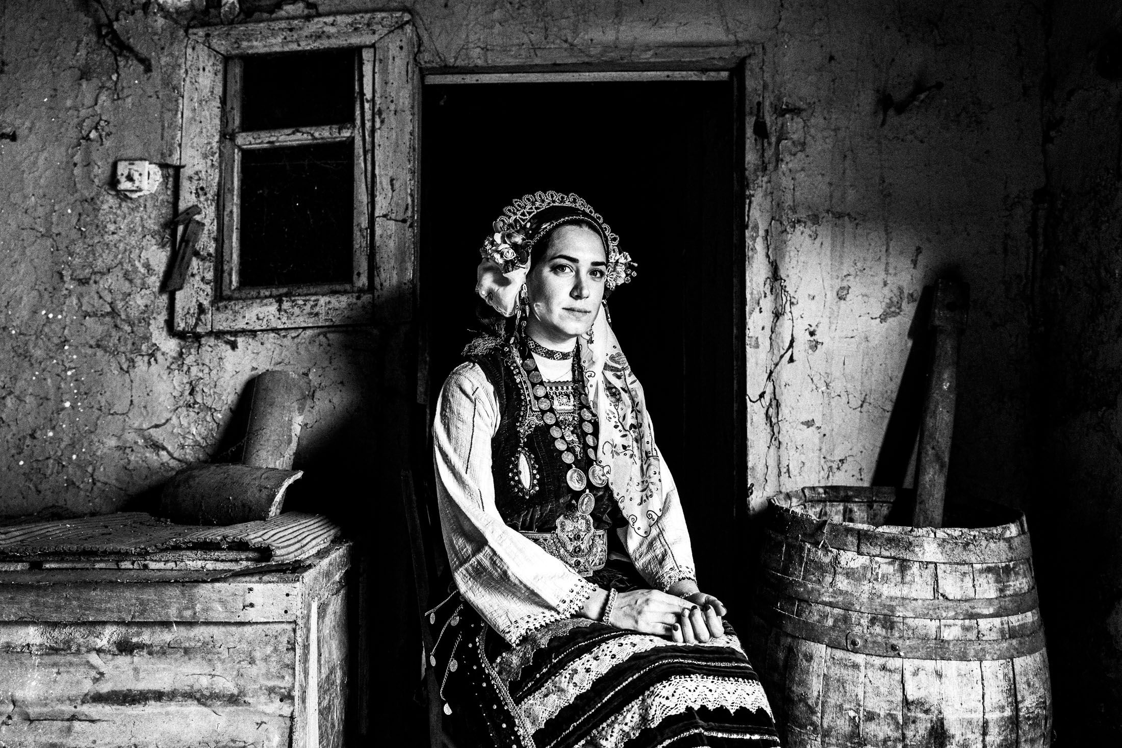 A woman wearing the local costume of Metaxades, sitting by the door inside an old local house.
