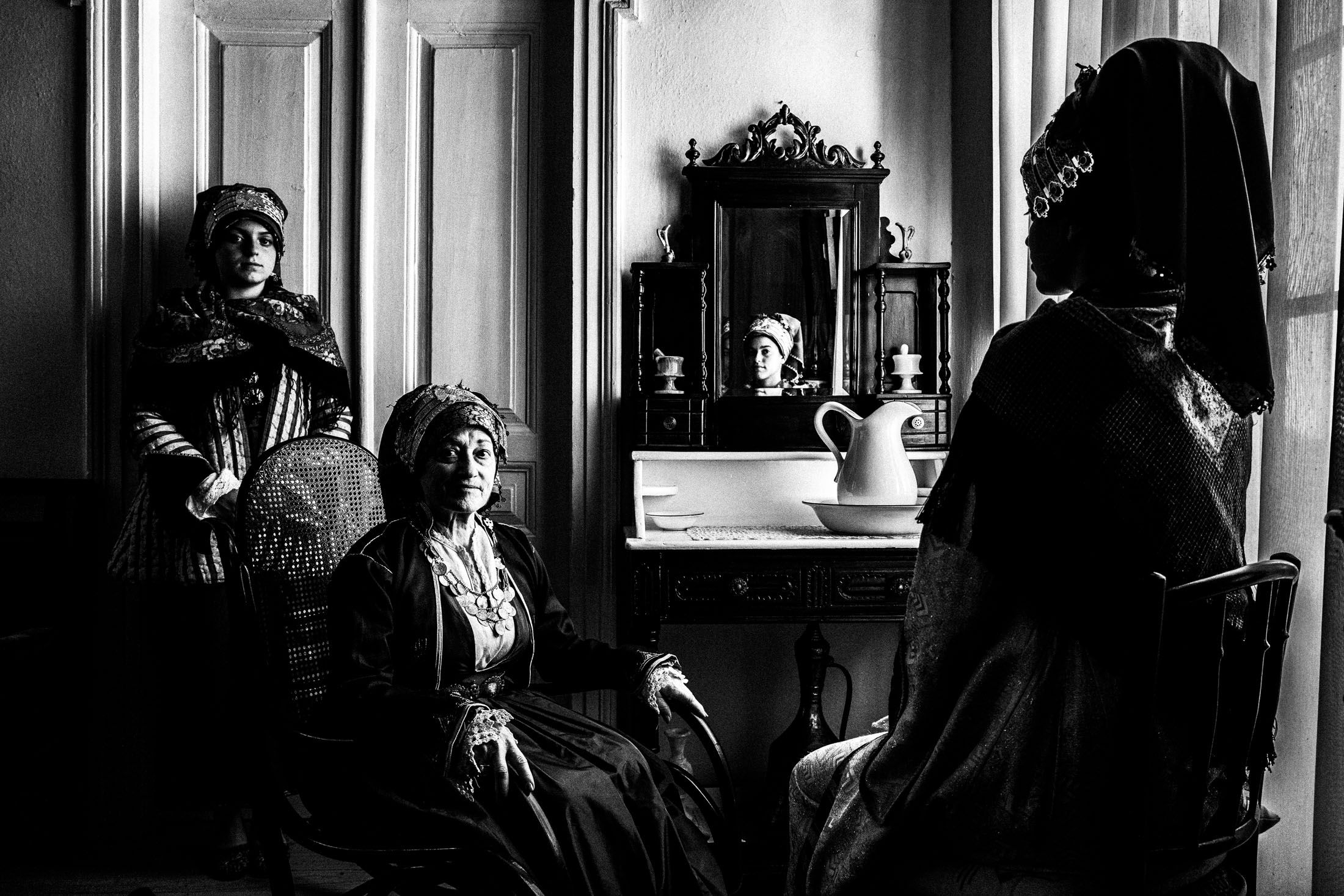 Three women wearing the local costumes of Symi, inside a local house