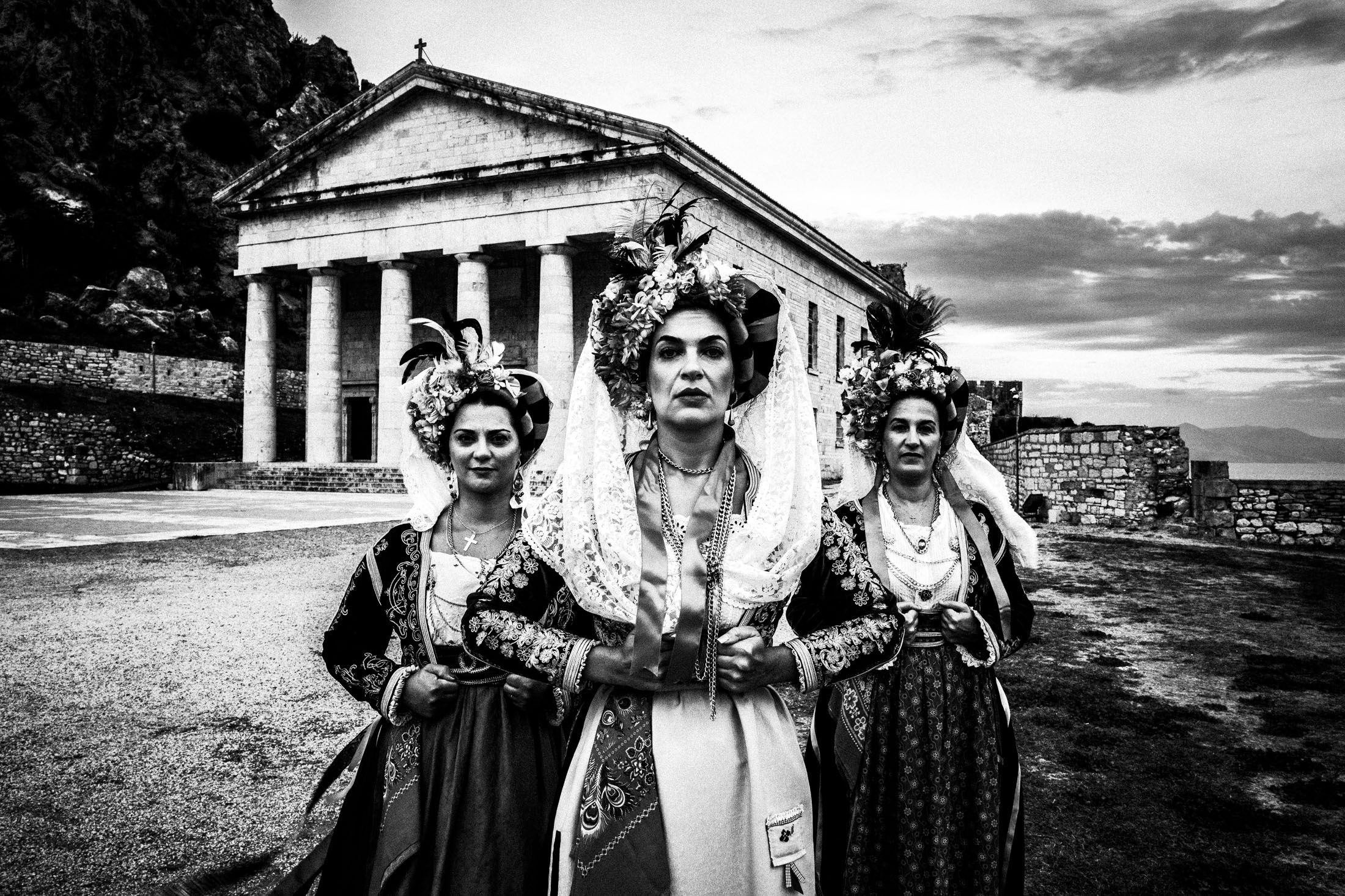 Three women in the costumes of Central Corfu posing in formation inside the old fortress