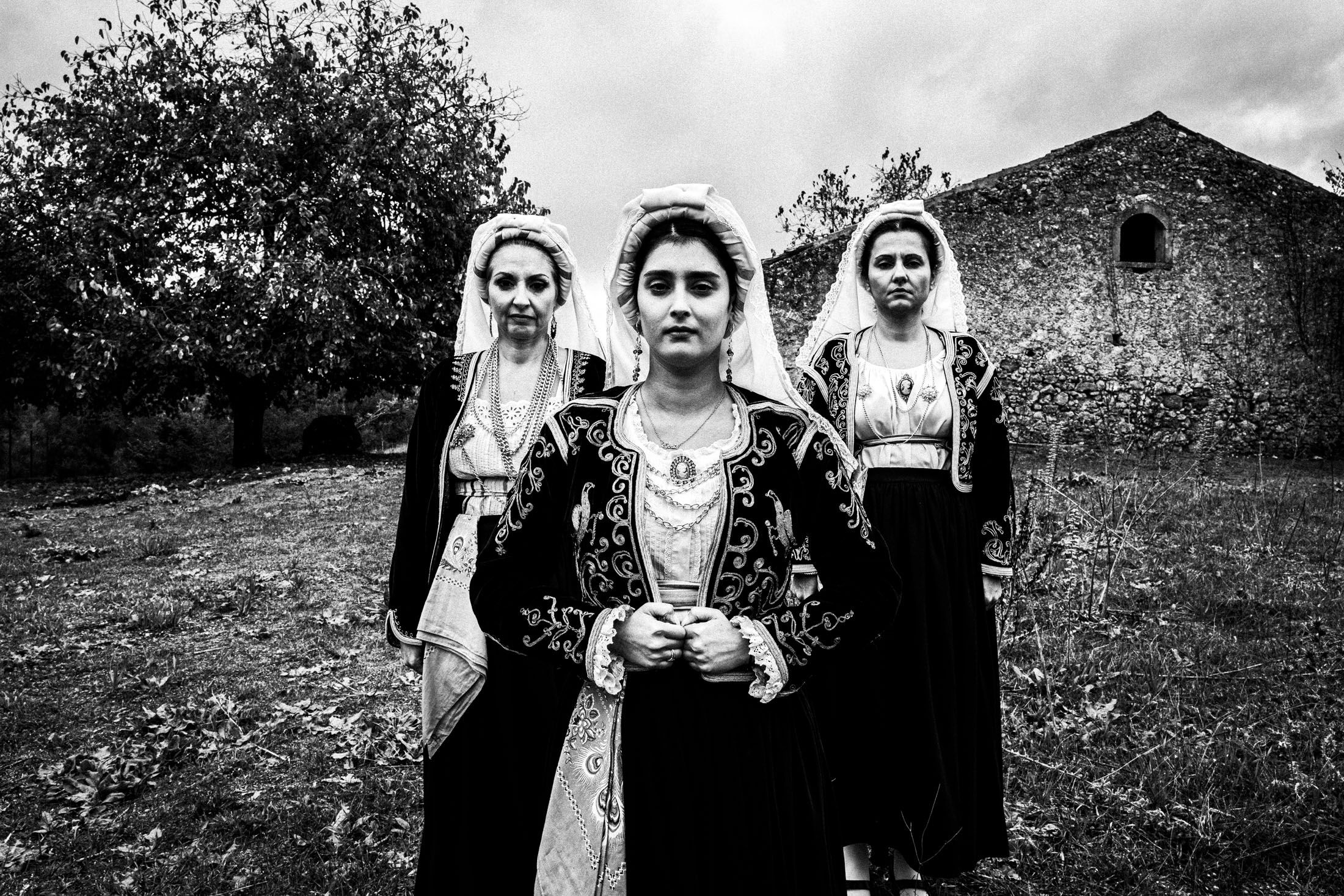 Three women in the costumes of Northern Corfu posing at a local field