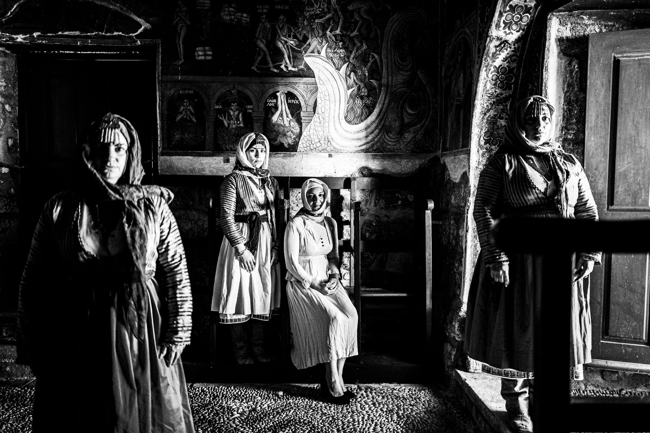 Four women wearing the costumes of Gennadi, Rhodes, inside a local church with side light