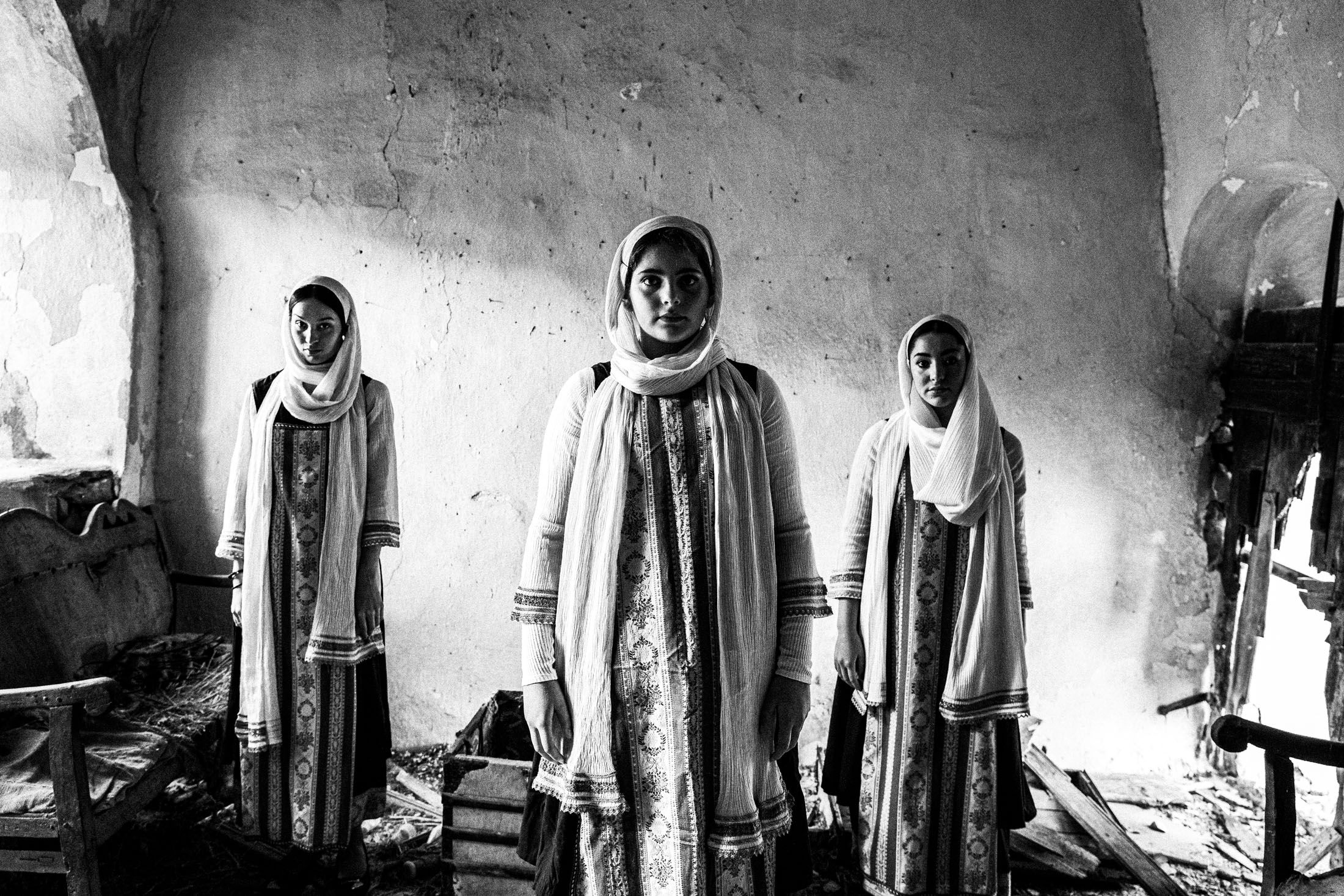 Women in the local dresses of Elata standing inside an old abandoned house