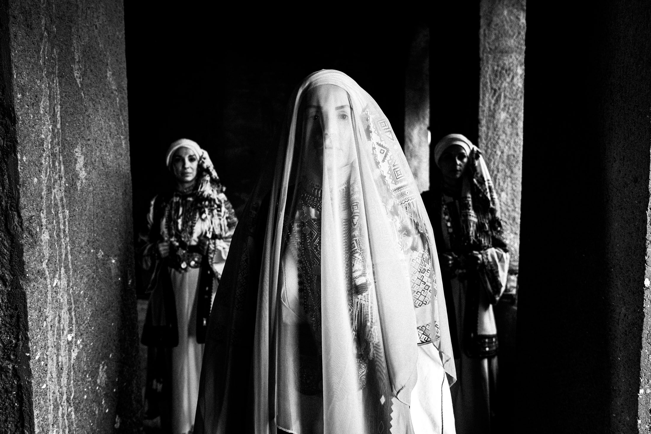 A veiled bride and two women wearing the local costumes of Kyparissia, Peloponnese, standing inside a local house