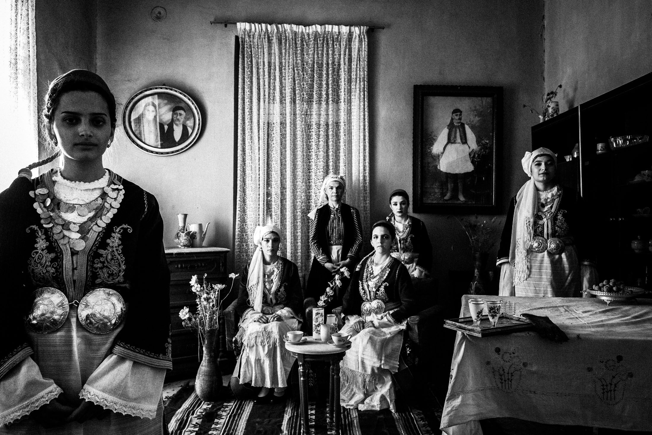 Six women wearing the traditional costume of Tegea, inside a local house