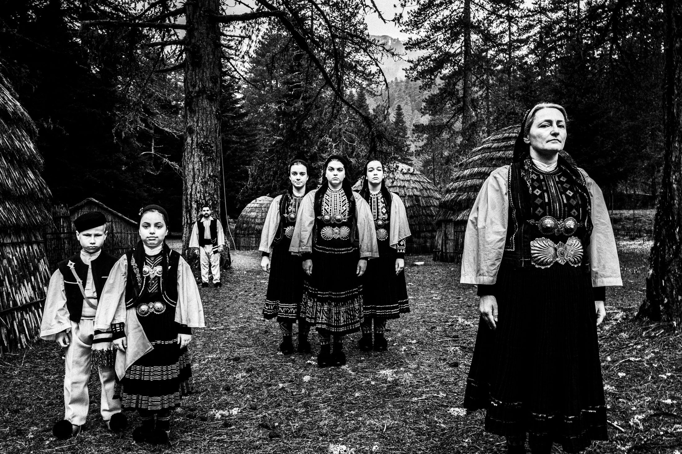 A group of people wearing the costumes of the nomadic grouop of Sarakatsani at Gyftokampos by traditional huts
