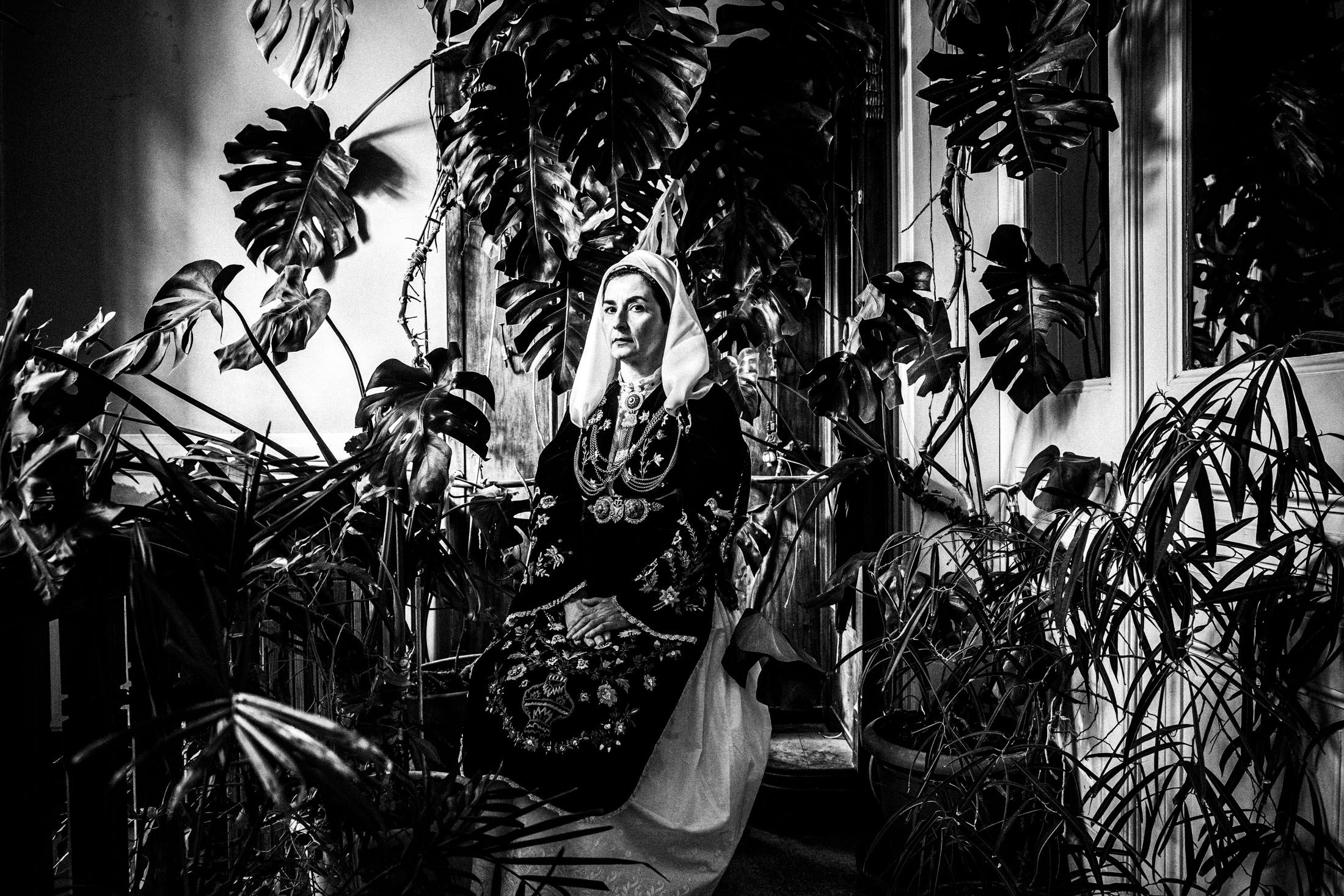 A woman wearing the costume of Martino sitting by a huge monstera plant at a local house