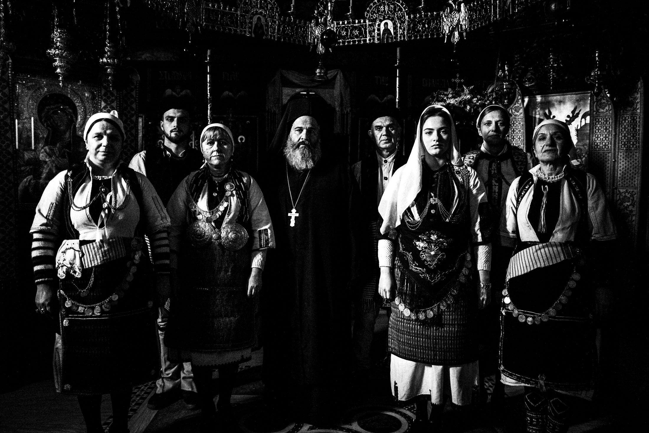 People wearing the local costumes of Klardorrachi, Florina, standing around a priest inside a local church