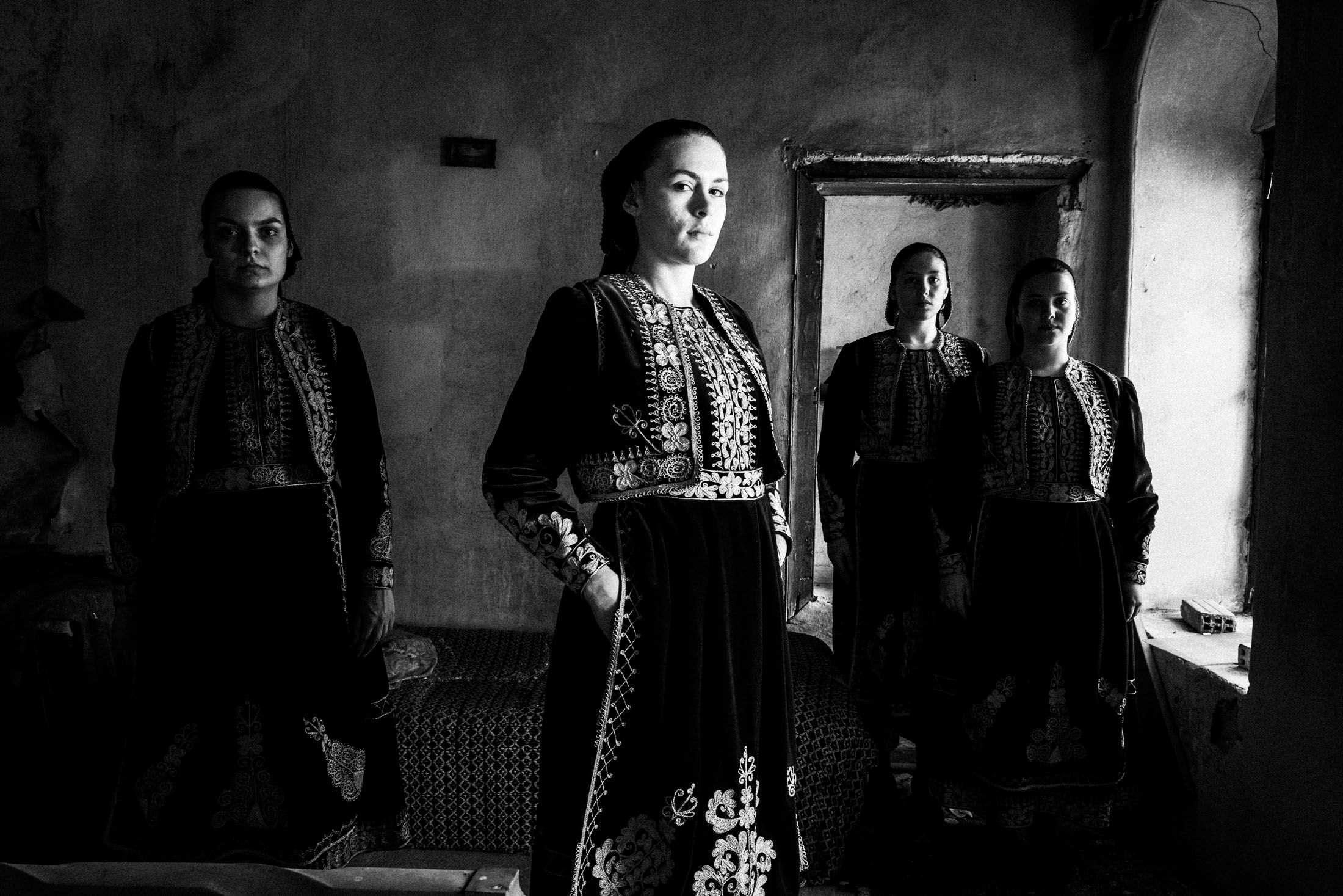 Four women wearing the local costumes of Filiates in Epirus, standing inside a local abandoned house.