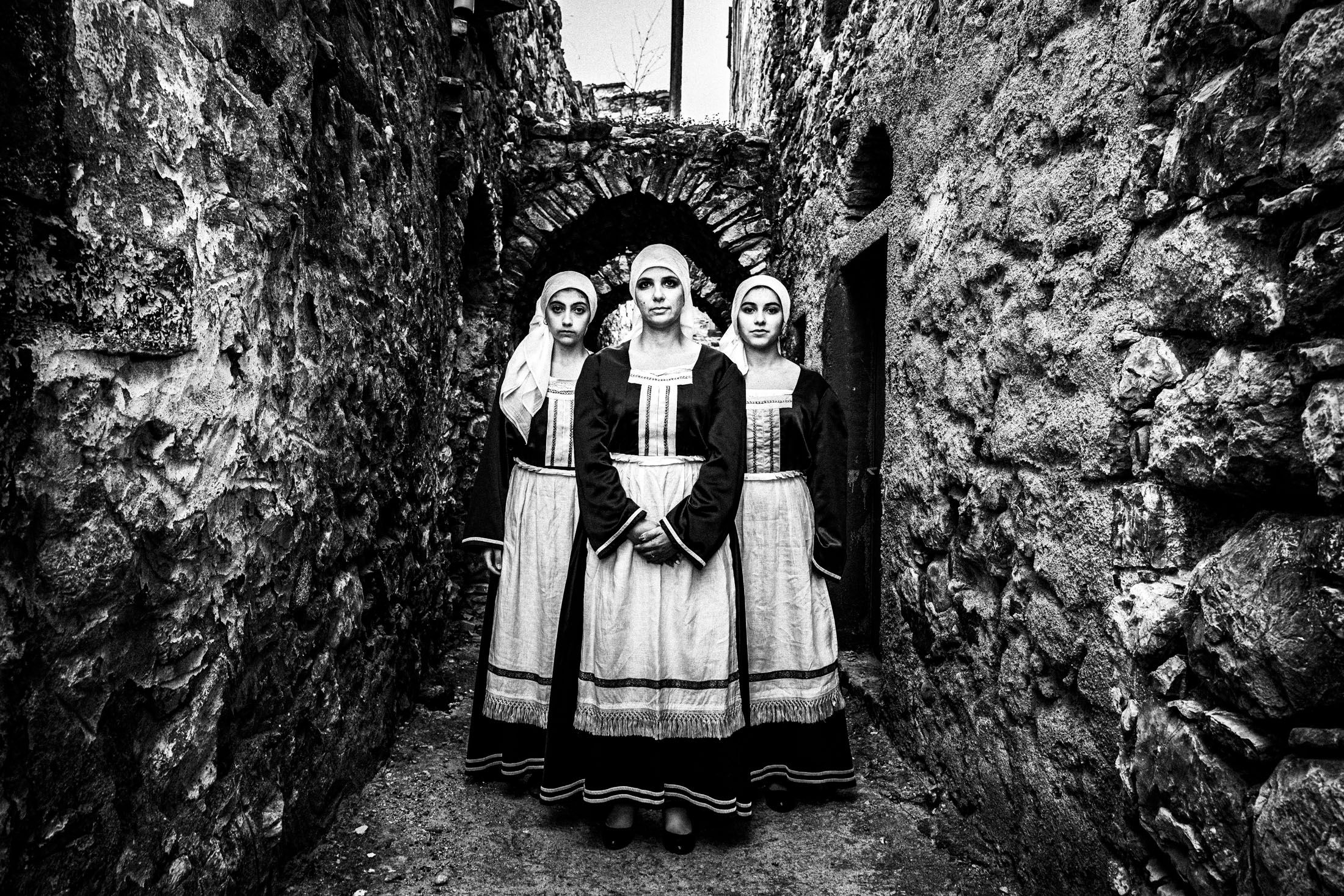 Three women standing in formation at the streets of Chalkio, Chios, wearing the local attire.