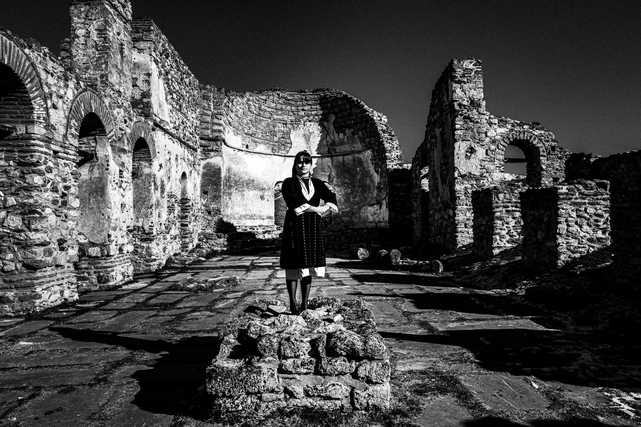 A woman standing inside the cathedral of St .Achillios of Prespes, wearing the local dress