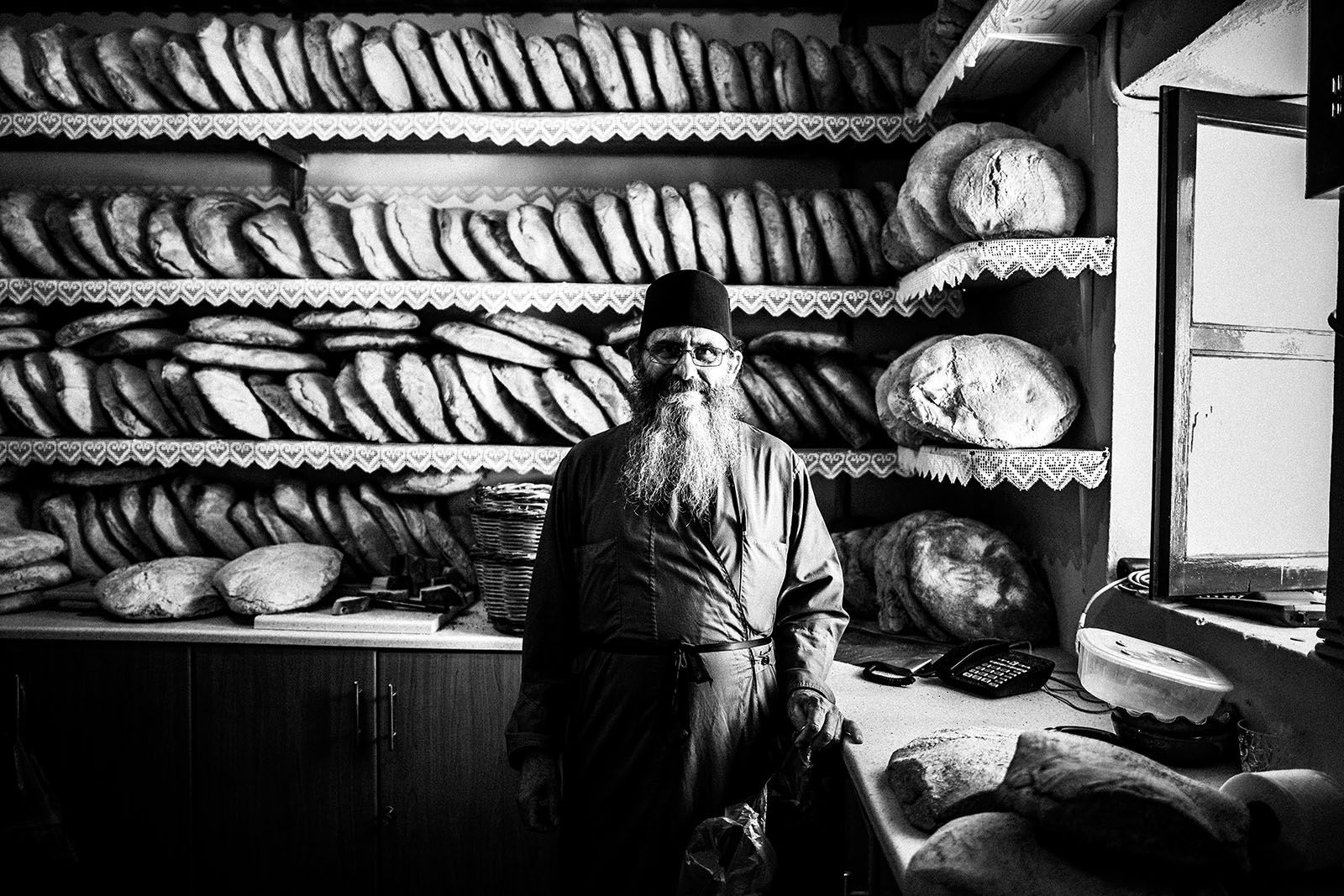 A priest standing inside a bread pantry at Agia Paraskevi monastery in Amorgos