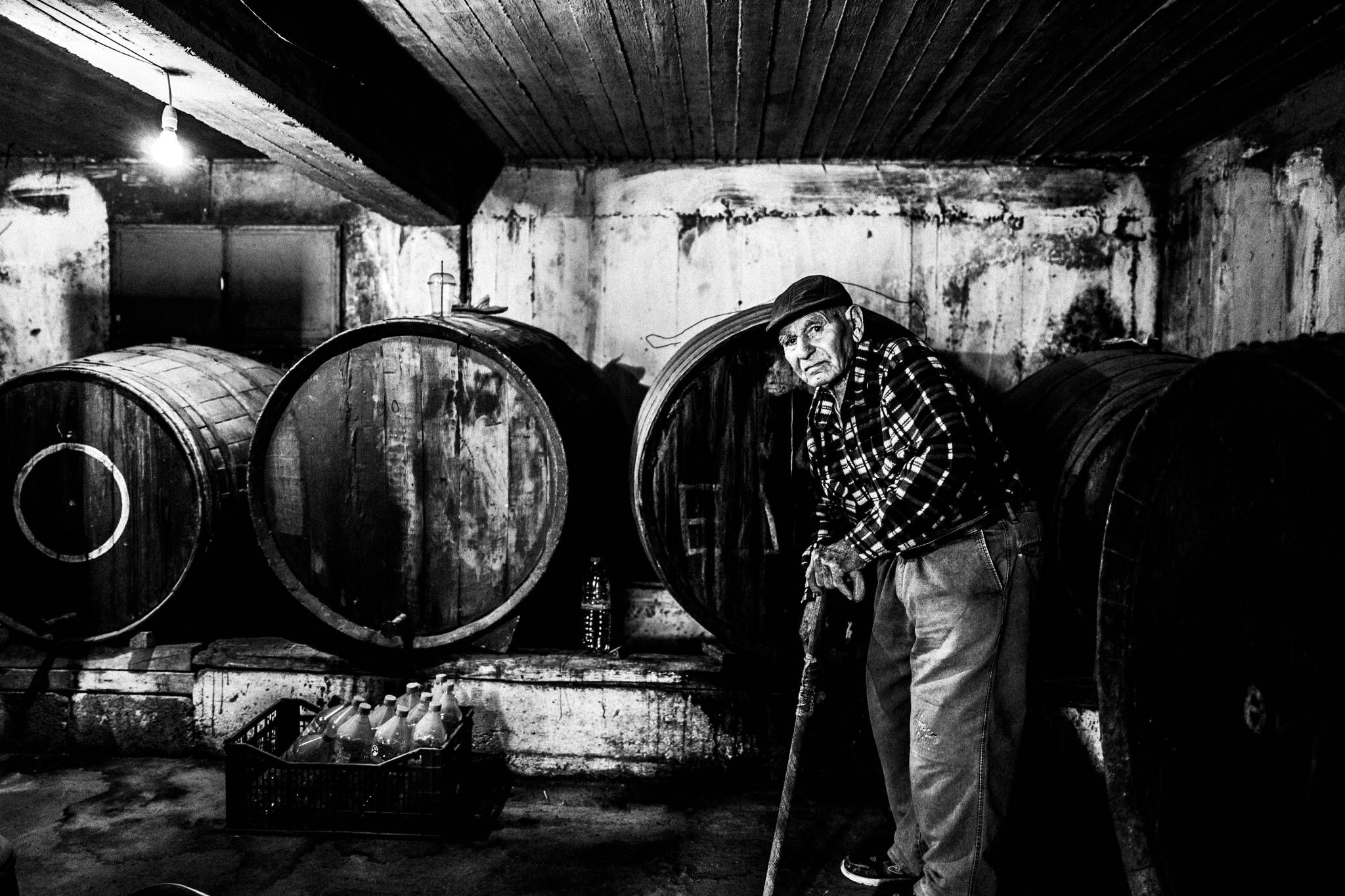 Traditional winemaker tasting wine from a barrel in Santorini.